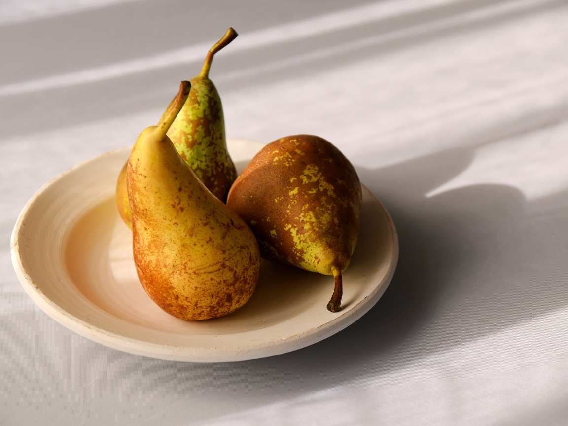 Три груши на тарелке на столе