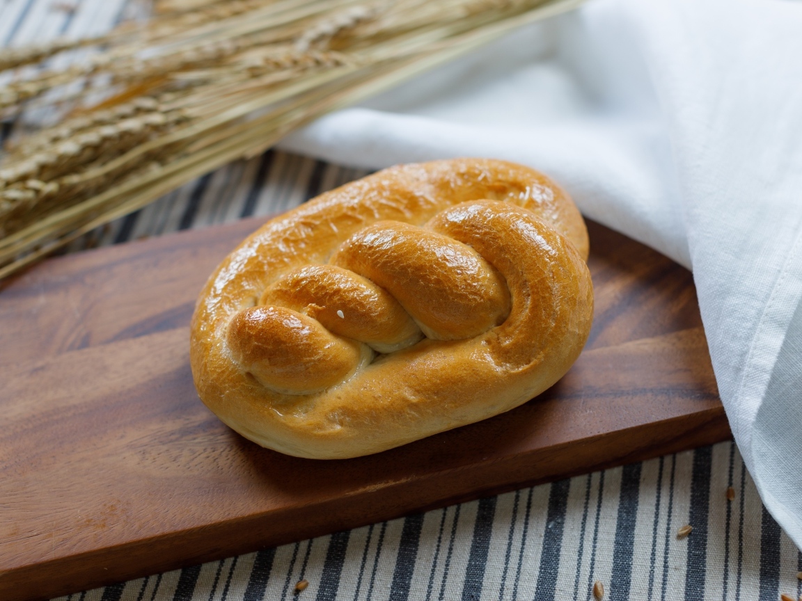 Булочка на столе с колосьями пшеницы