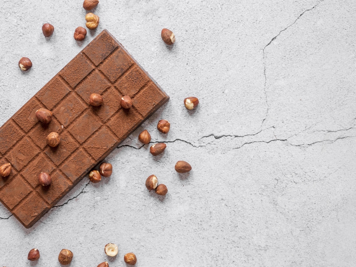 Молочная шоколадка с орехами на сером столе