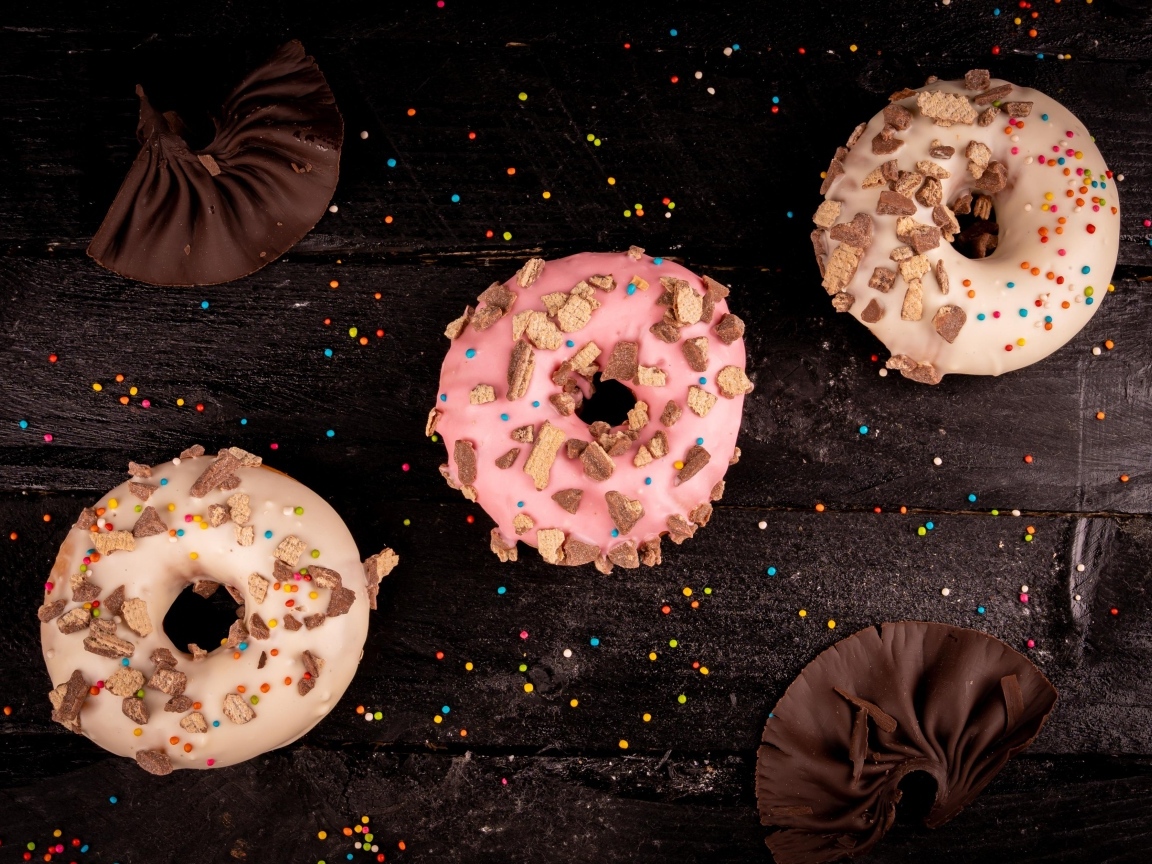 Три сладких пончика на черном столе
