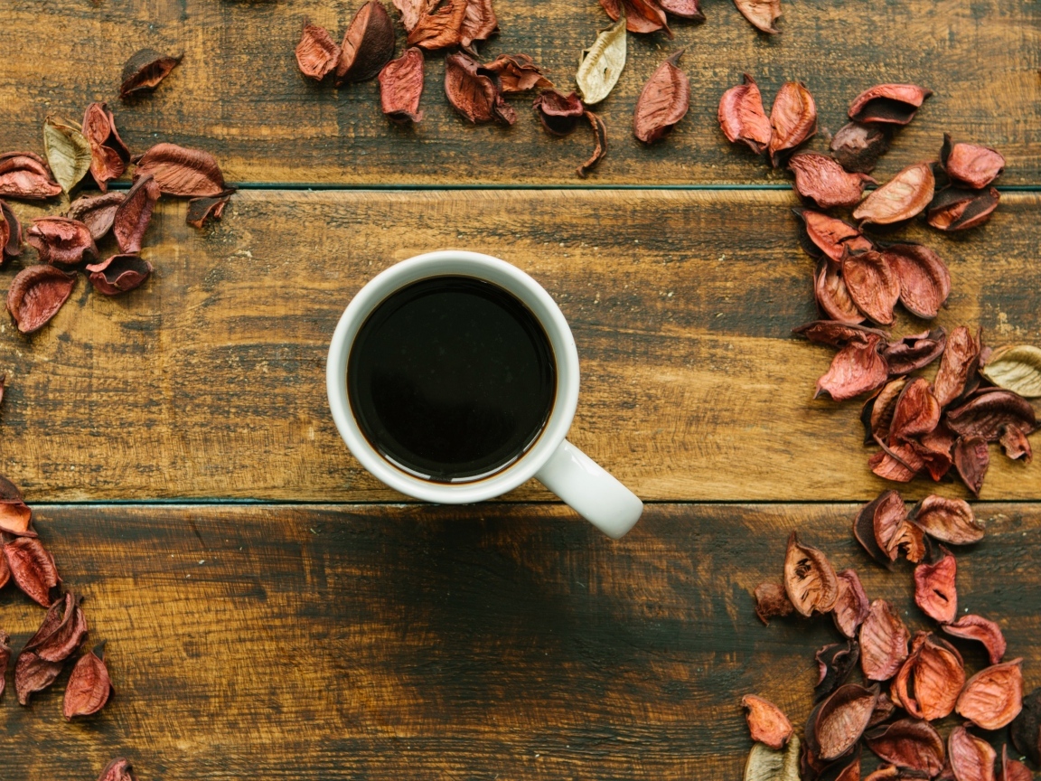 Чашка кофе с опавшими листьями на деревянном столе