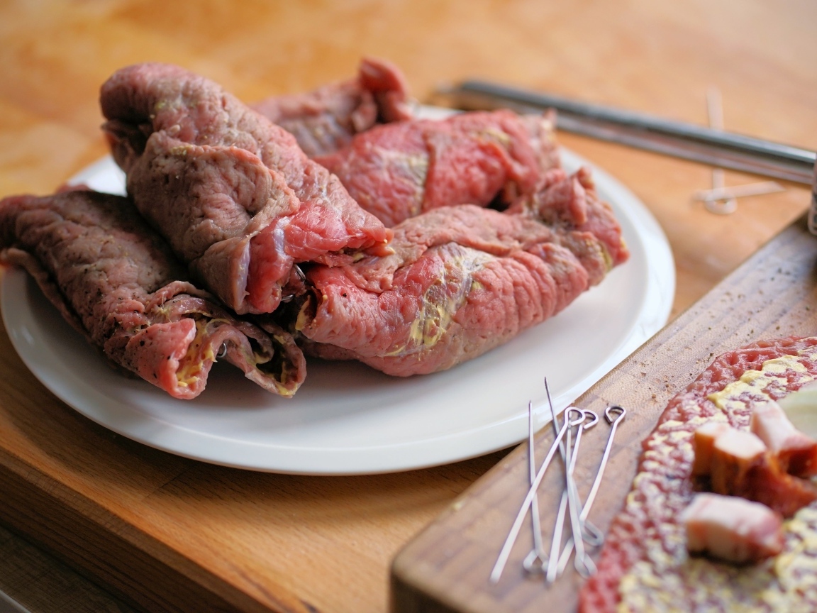 Рулетики из свинины на большой белой тарелке