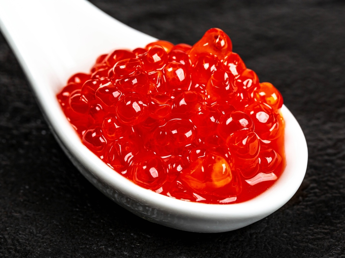 Красная икра на белой ложке крупным планом
