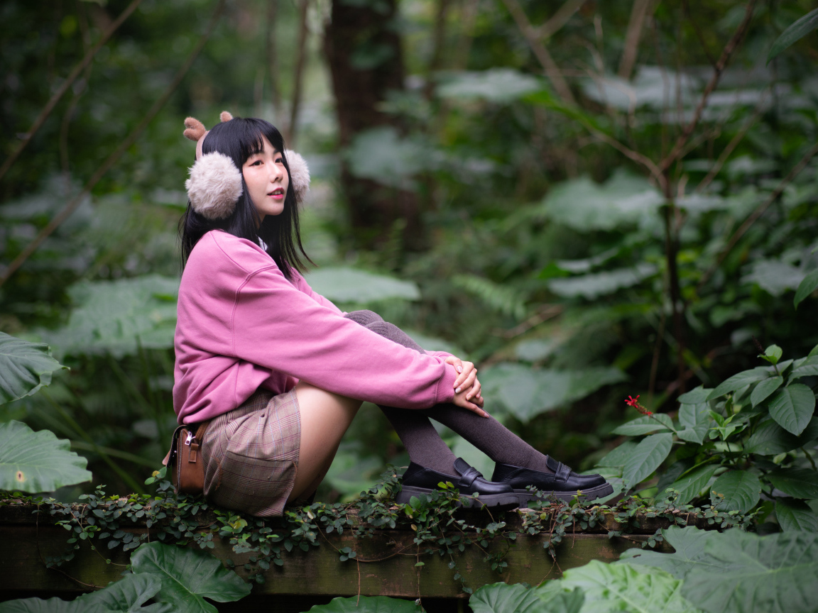 Девушка азиатка в розовом наряде сидит в зарослях