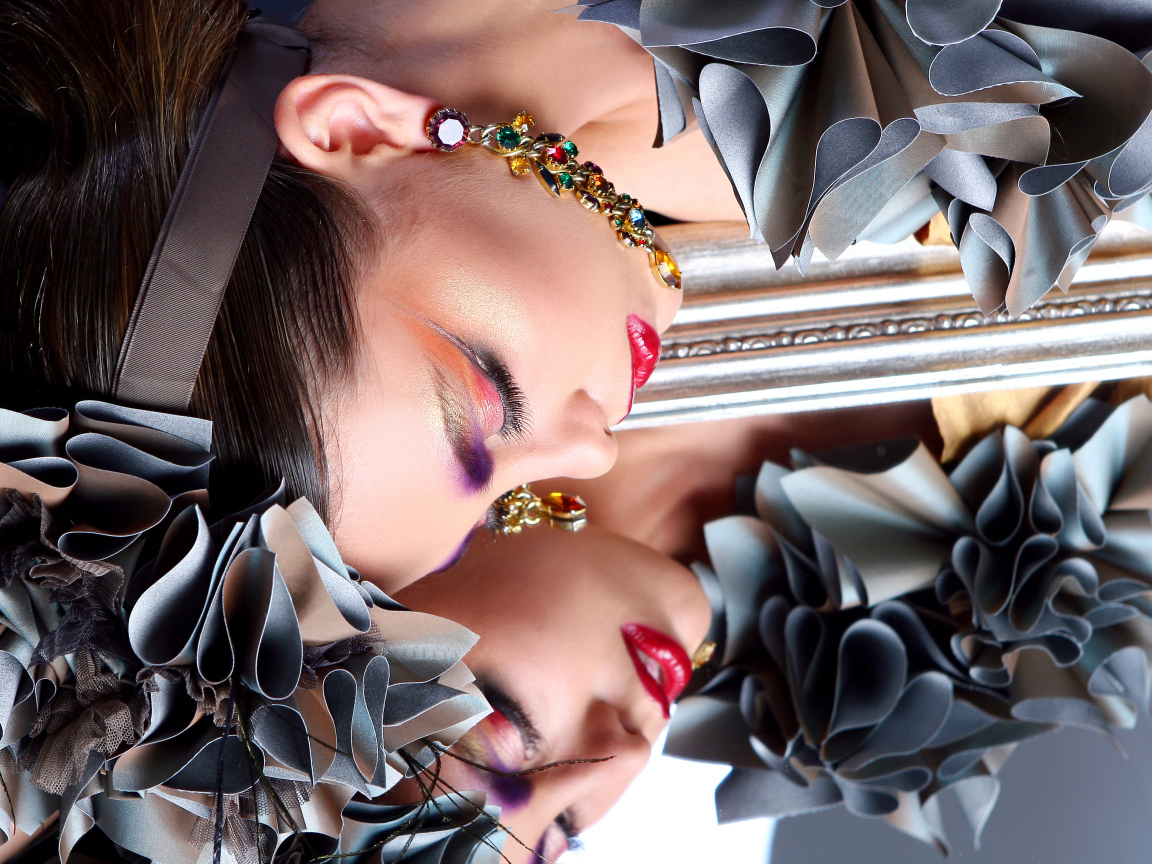 Красивая девушка с ярким макияжем отражается в зеркале