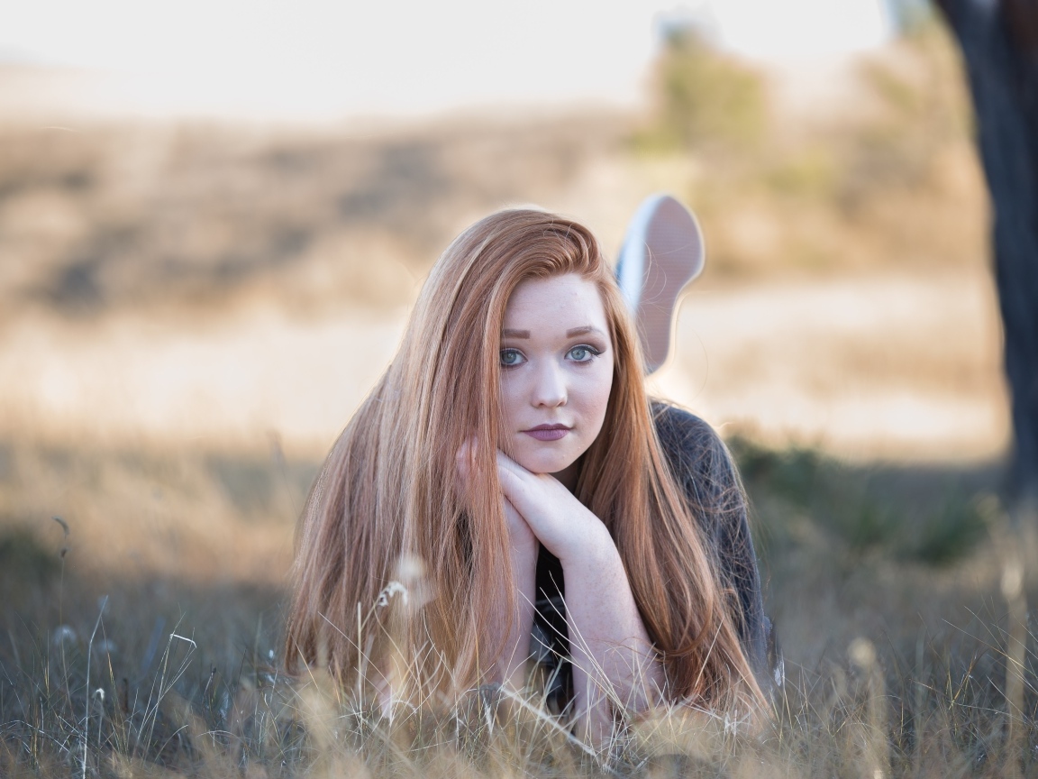 Красивая рыжеволосая девушка лежит на траве