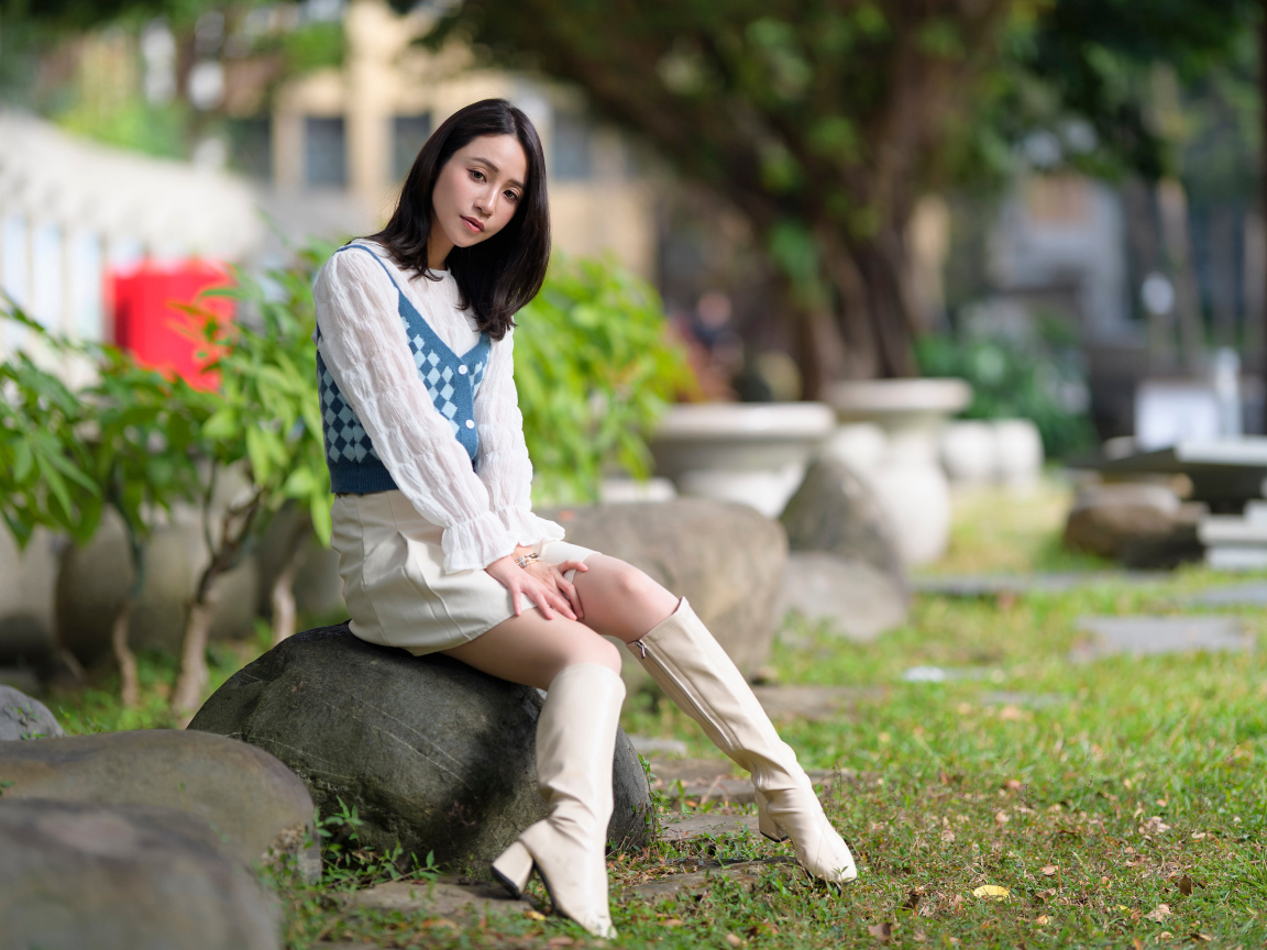 Милая девушка сидит на камне в парке