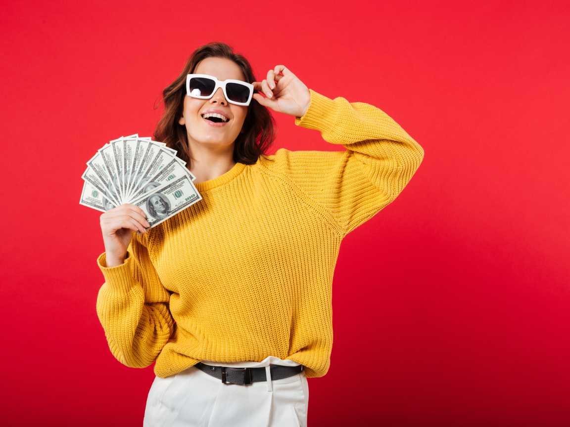 Девушка с веером из долларов на красном фоне