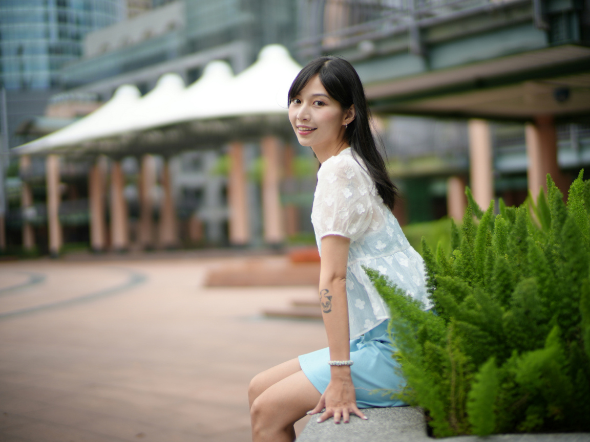 Улыбающаяся азиатка в белой блузке у дома