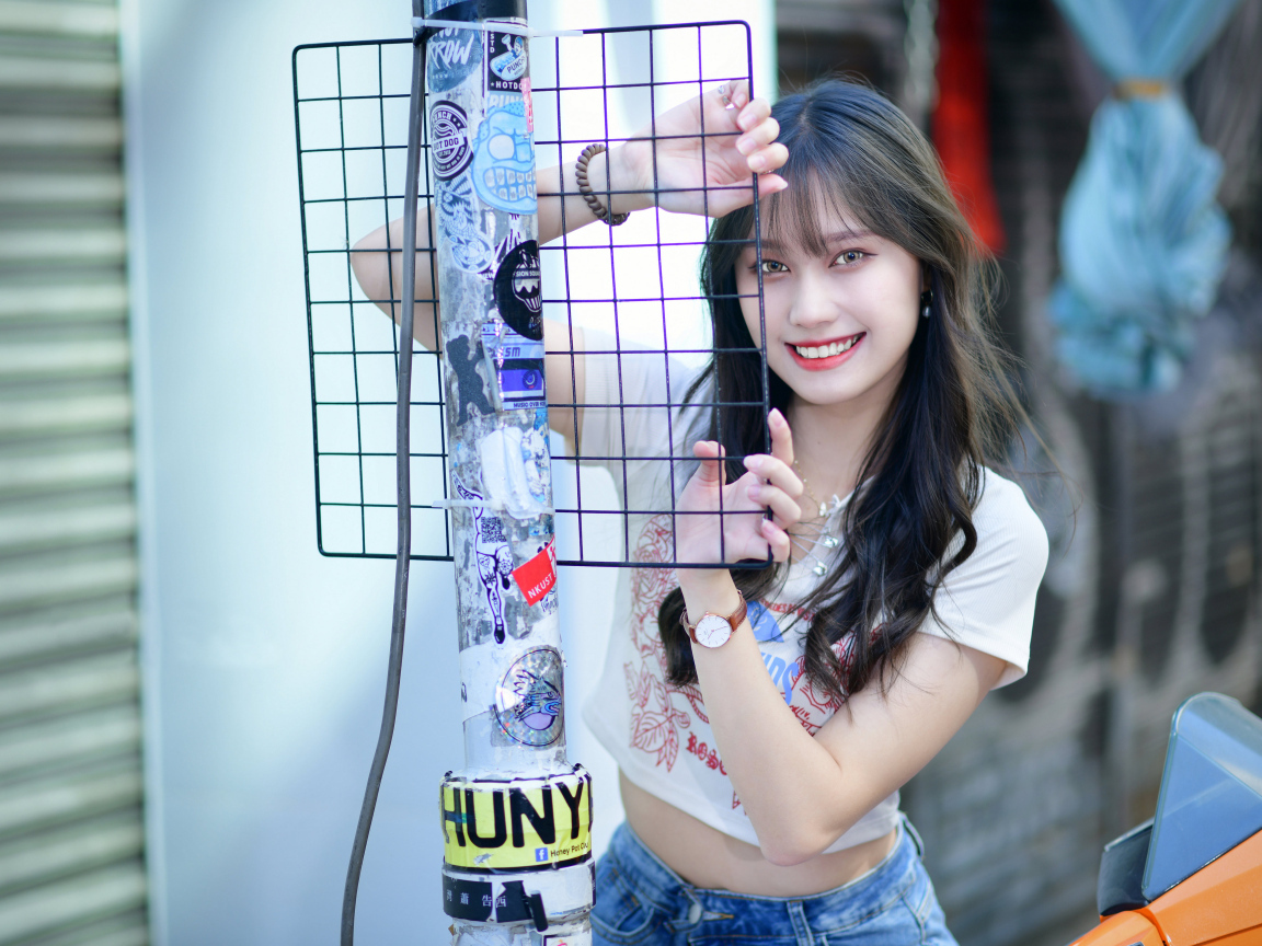 Улыбающаяся азиатка держится за сетку
