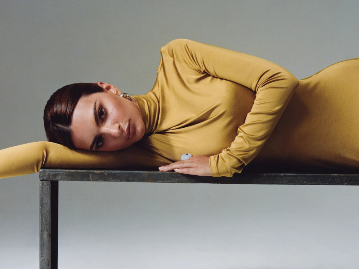 Красивая модель Эмили Ратаковски в желтом платье лежит на столе