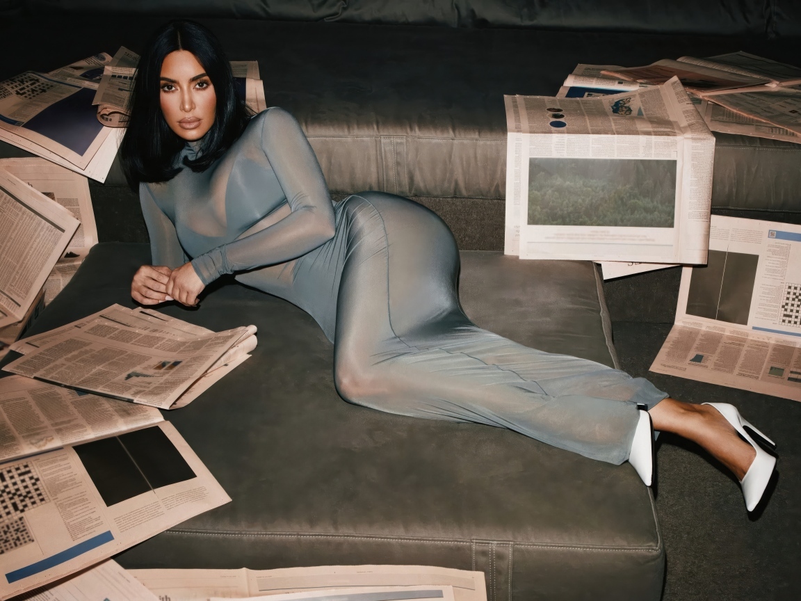 Модель Ким Кардашьян лежит на диване с газетами