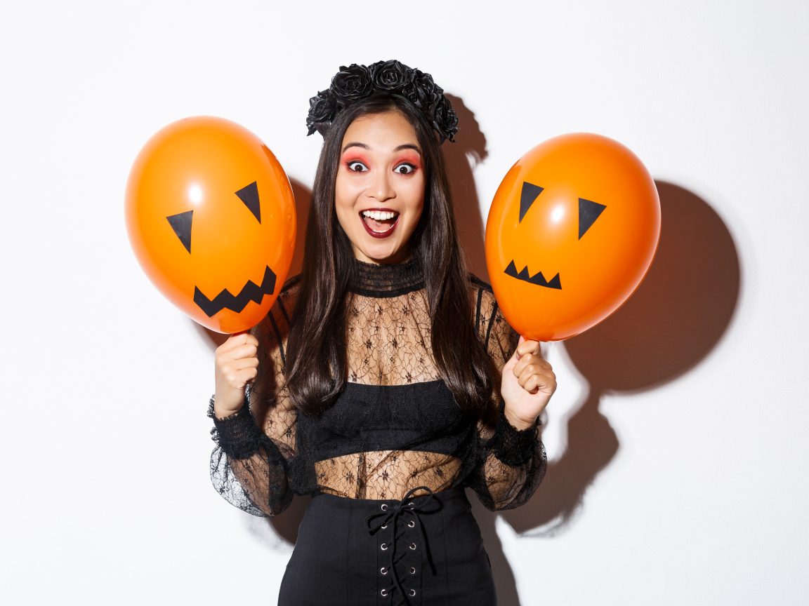 Девушка в костюме на праздник Хэллоуин с шариками в руках