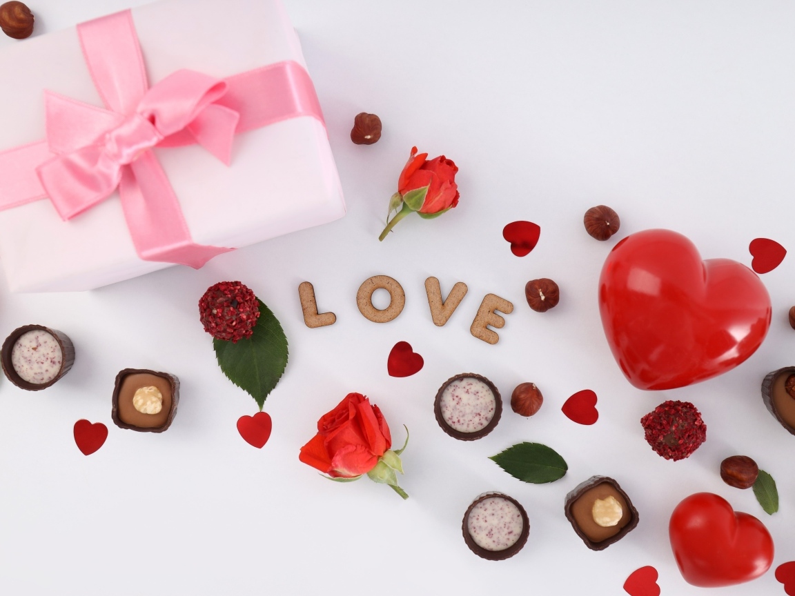 Подарок и сердечки с конфетами на столе на День Святого Валентина