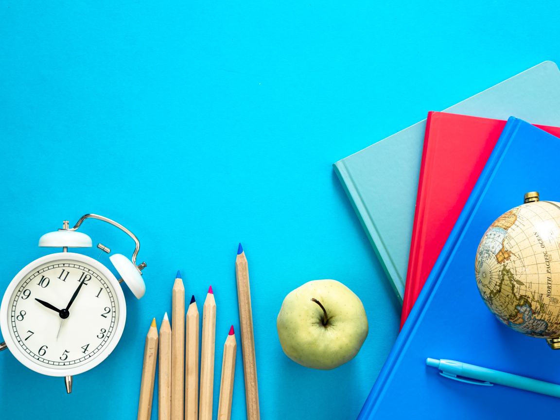 Книги на столе с глобусом, карандашами и будильником