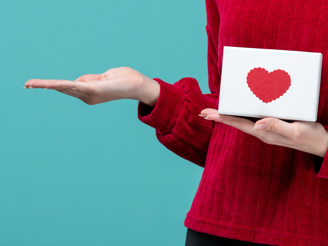 Коробка с сердцем в руке у девушки на голубом фоне