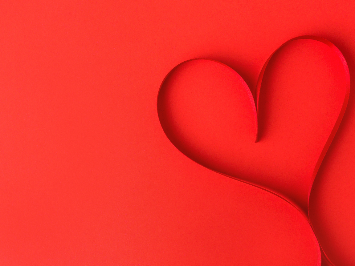 Сердце из атласной ленты на красном фоне