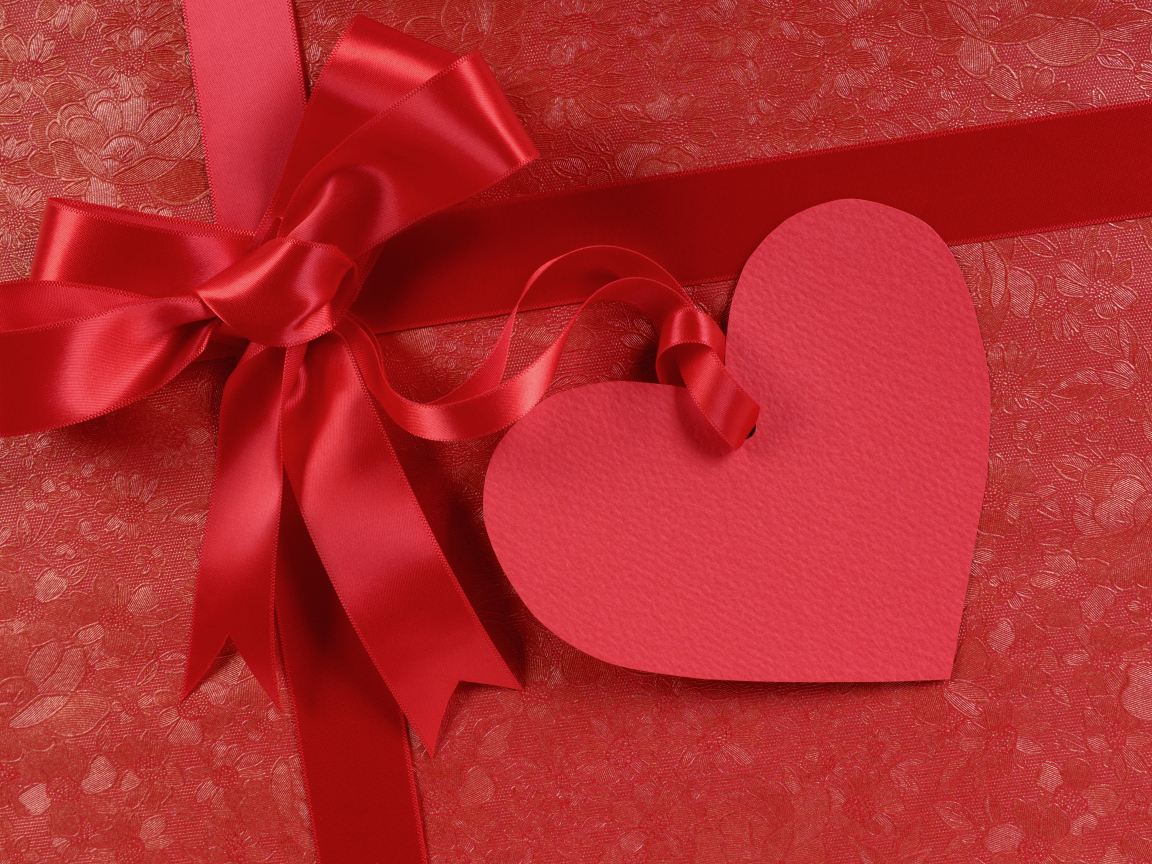 Бумажное сердце с бантом из атласной ленты на красном фоне