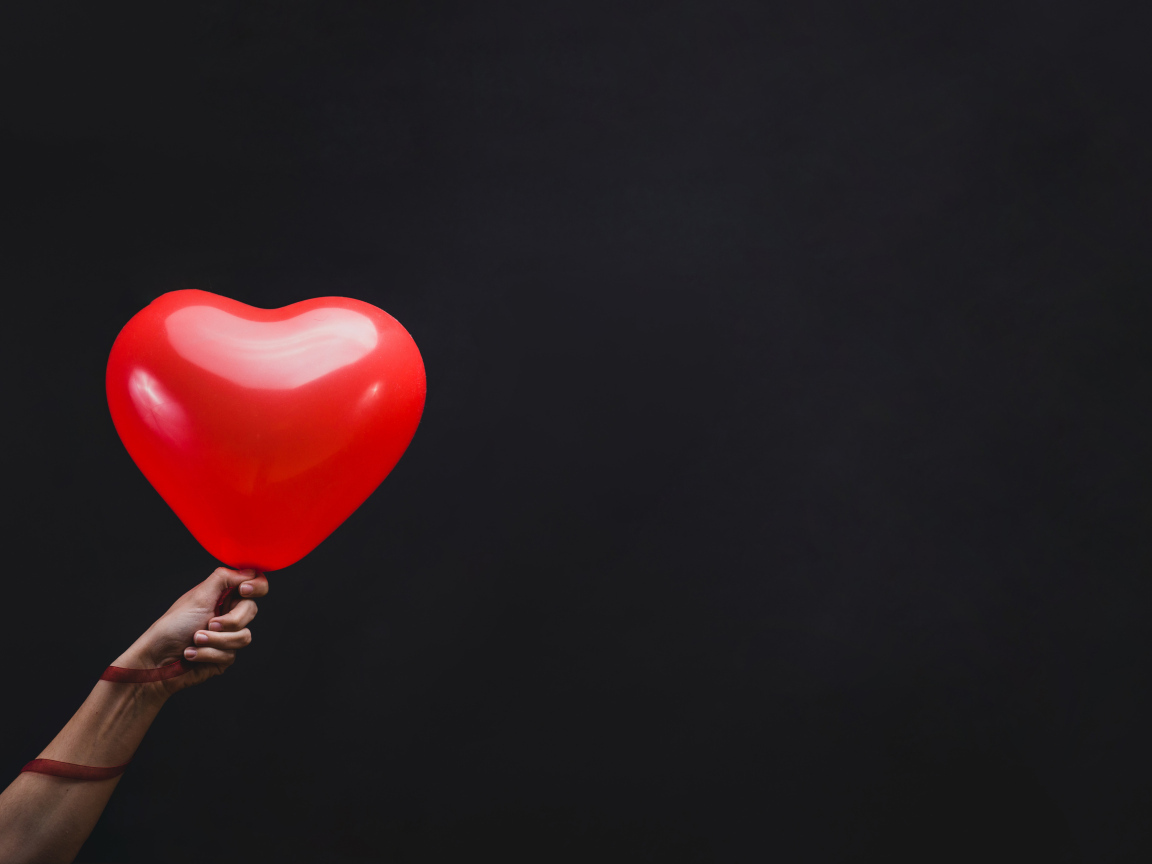 Красный шарик в форме сердца на черном фоне