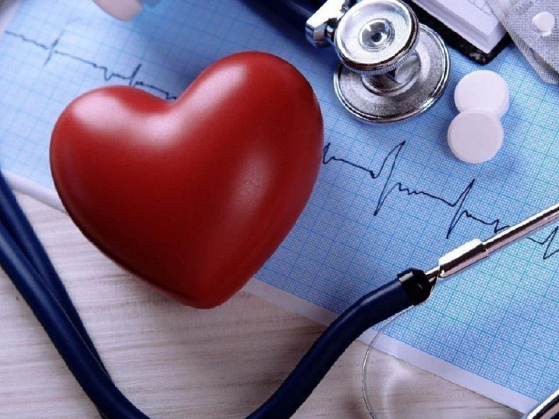 Красное сердце на столе с кардиограммой и стетоскопом