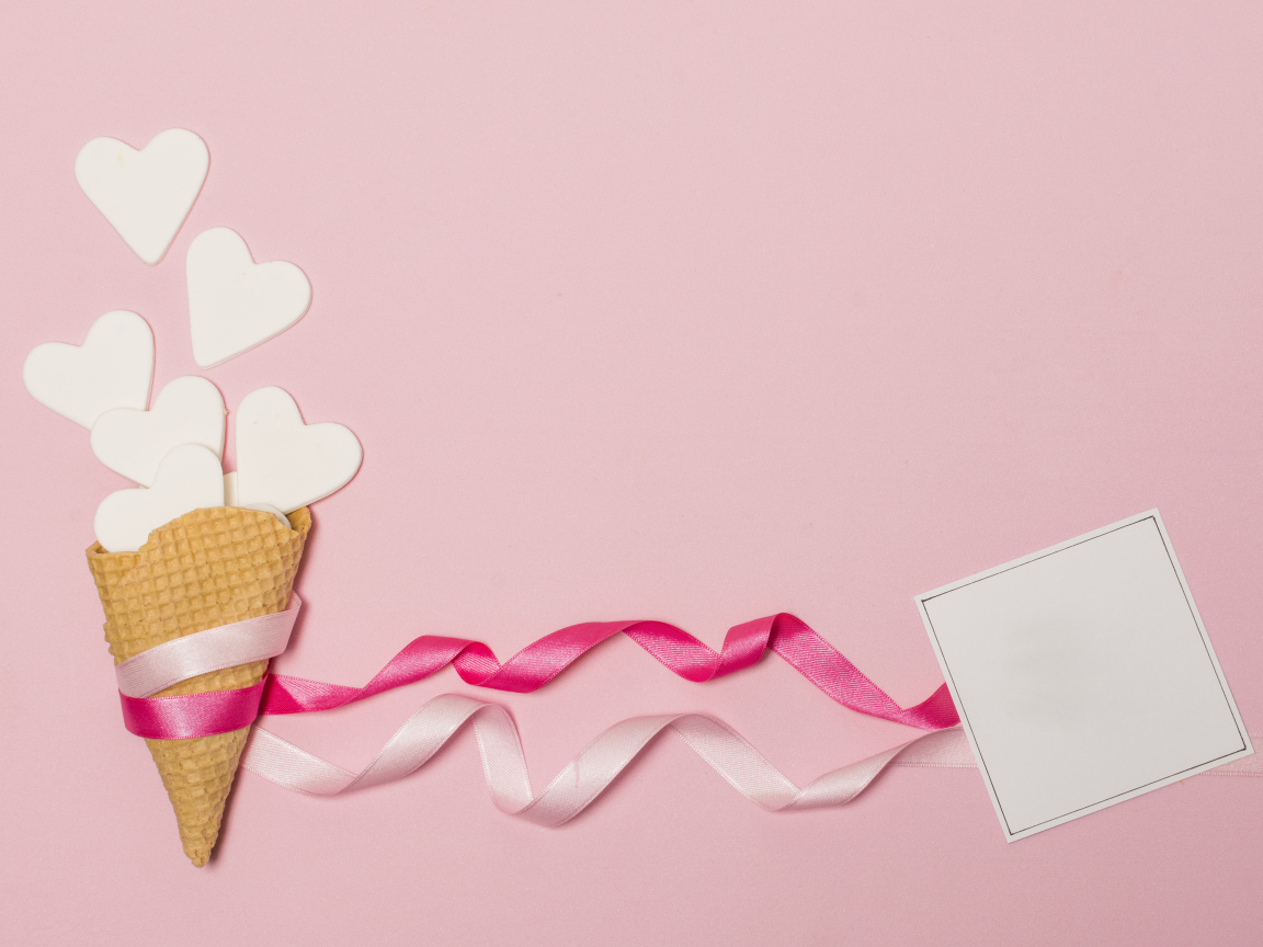 Вафельный рожок с сердечками, лентами и листом бумаги на розовом фоне