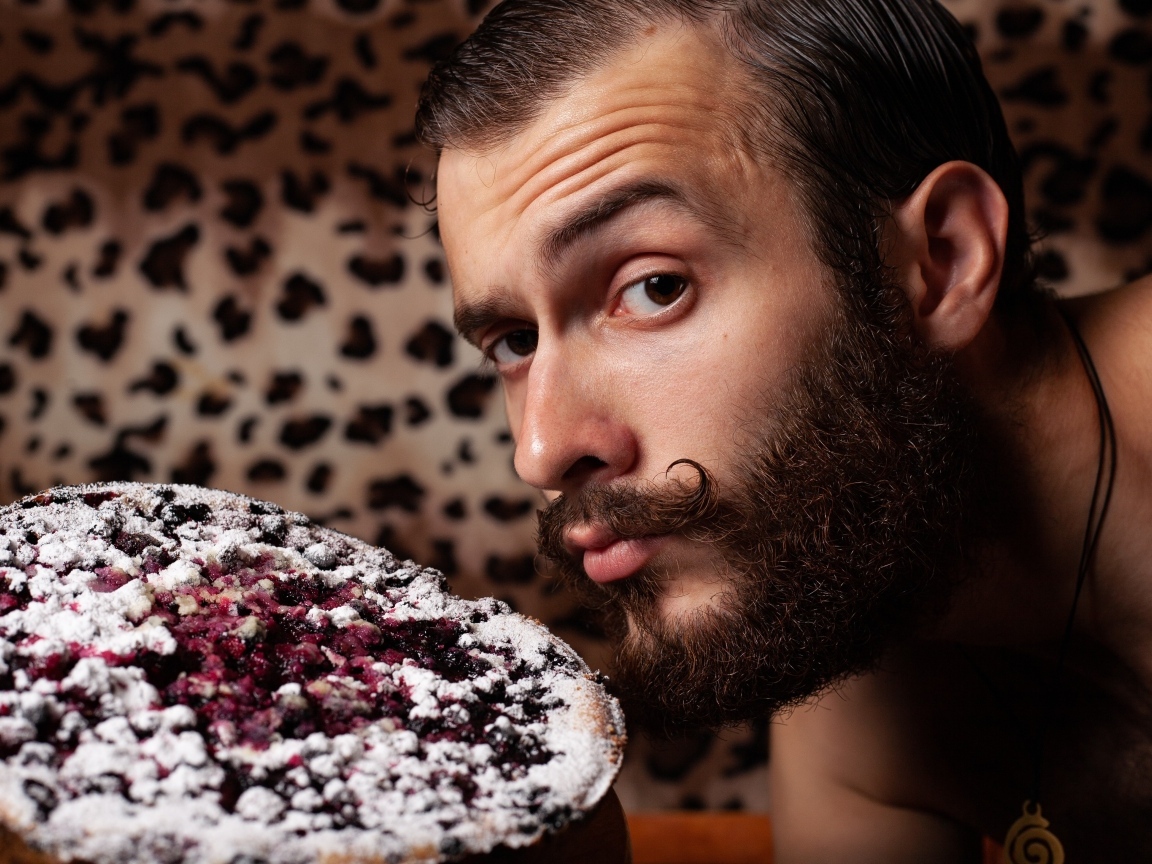 Мужчина с бородой держит сладкий пирог 