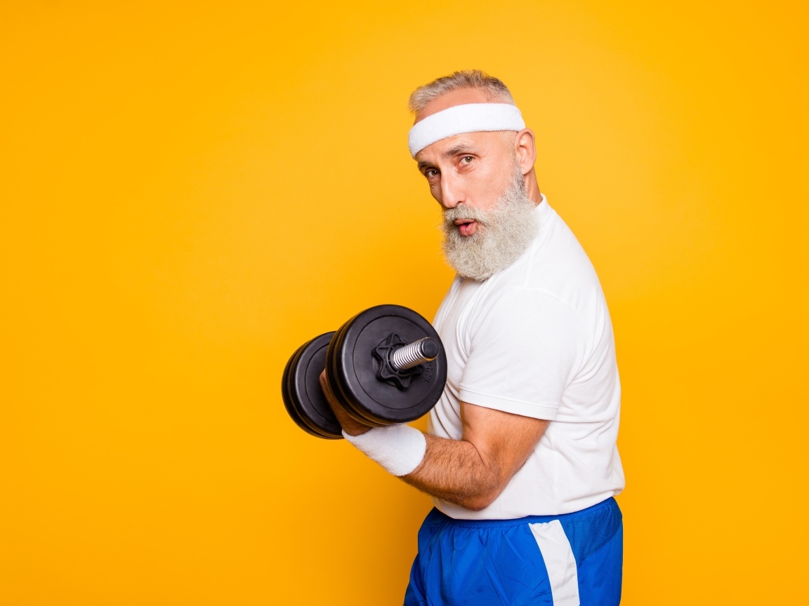 Спортивный мужчина с гантелей в руке на желтом фоне