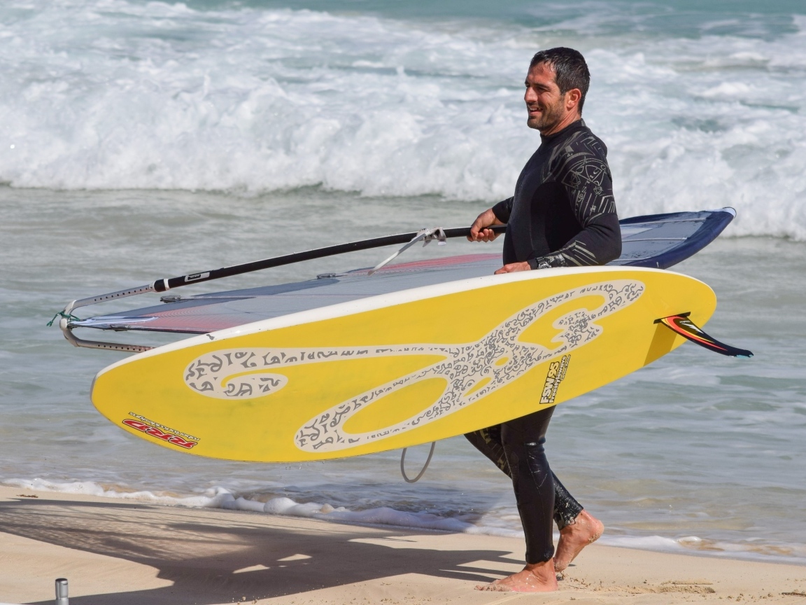 Мужчина серфер с доской на пляже