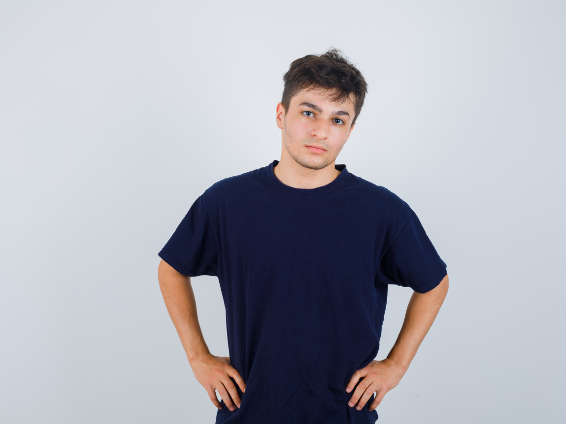 Молодой парень в синей футболке на сером фоне