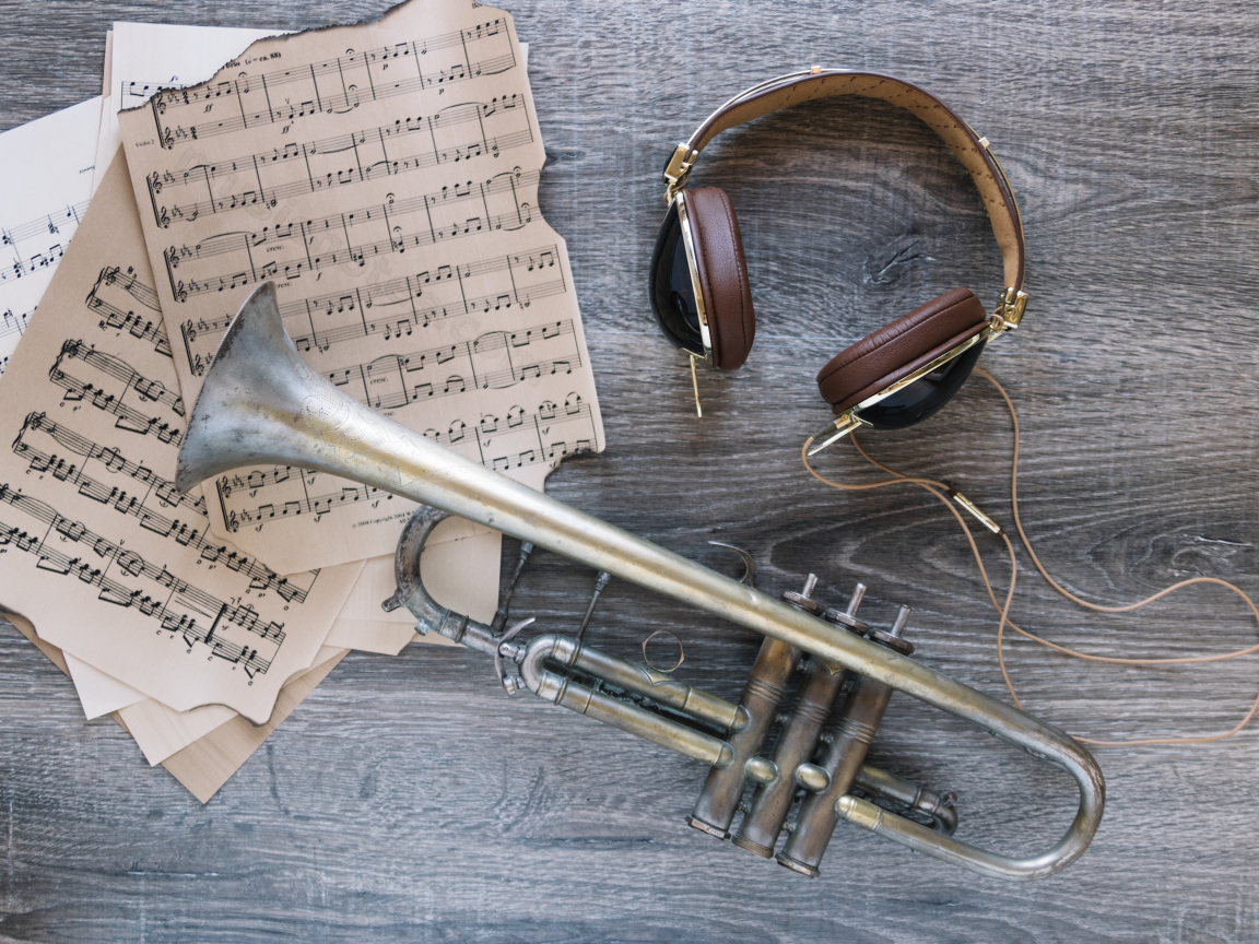 Старые ноты, наушники и труба на столе