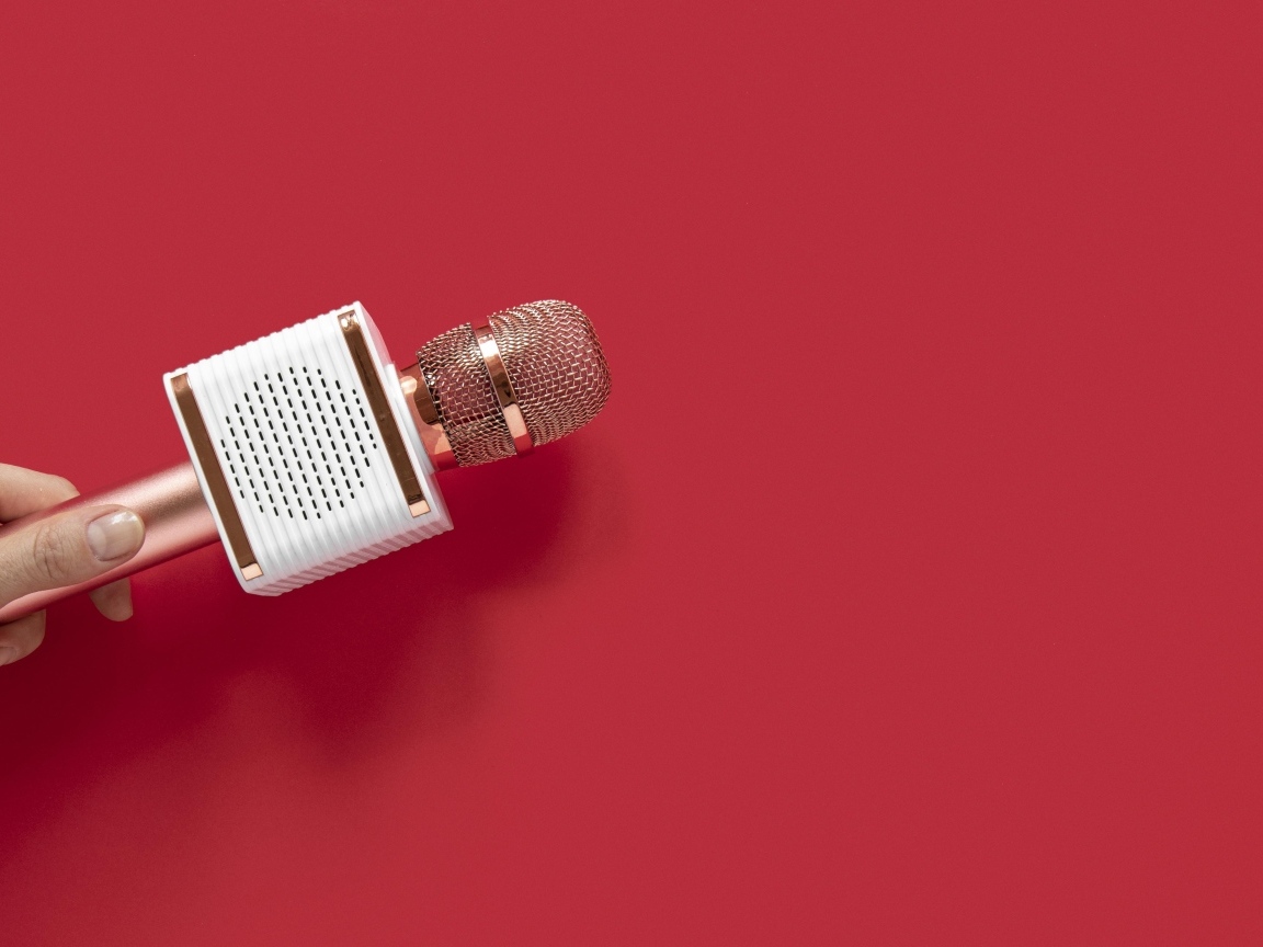 Радиомикрофон в руке на красном фоне