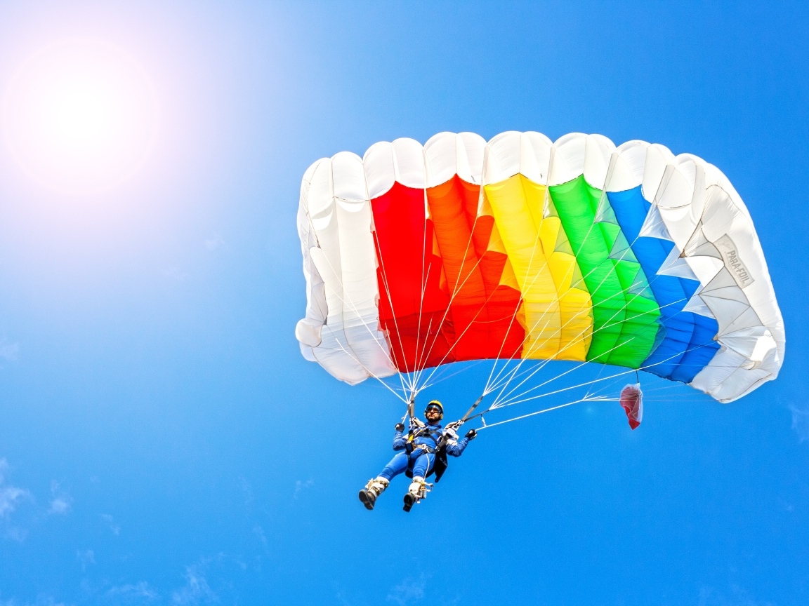 Парашютист в голубом небе в лучах солнца
