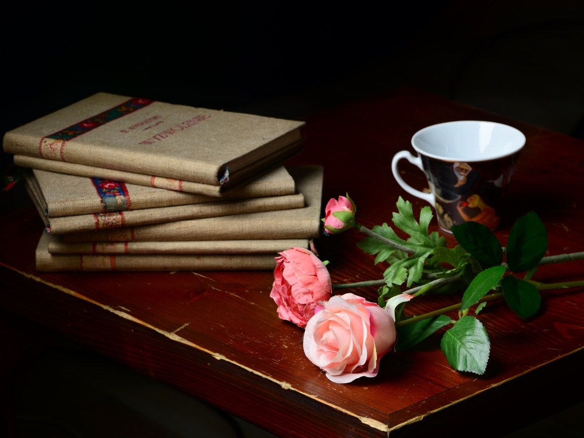Книги на столе с цветами и чашкой