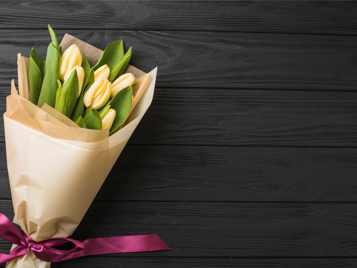 Букет желтых тюльпанов в бумажной упаковке с лентой