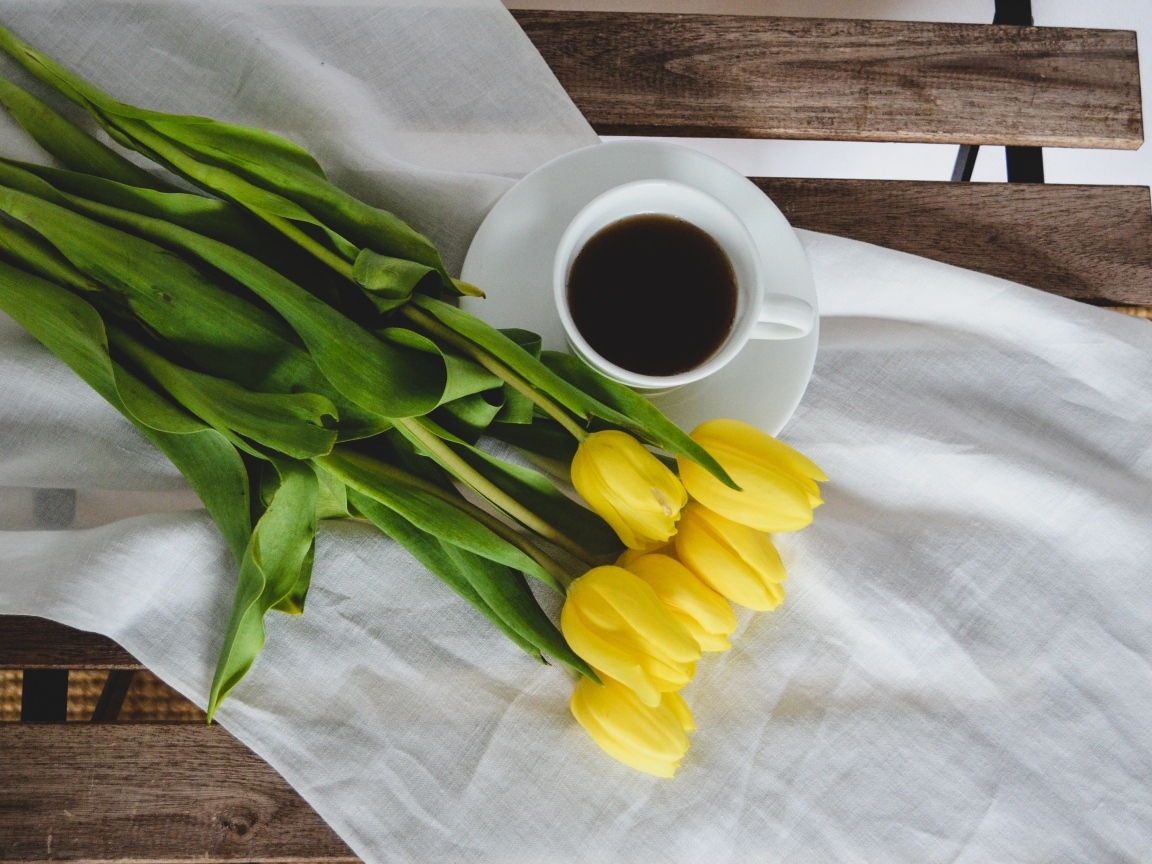 Букет желтых тюльпанов с чашкой кофе на лавке