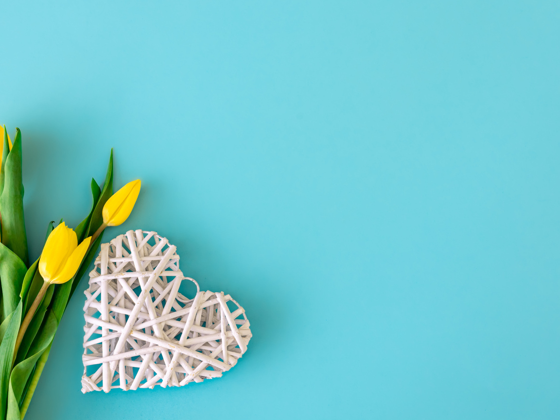 Белое плетеное сердце с букетом желтых тюльпанов на голубом фоне