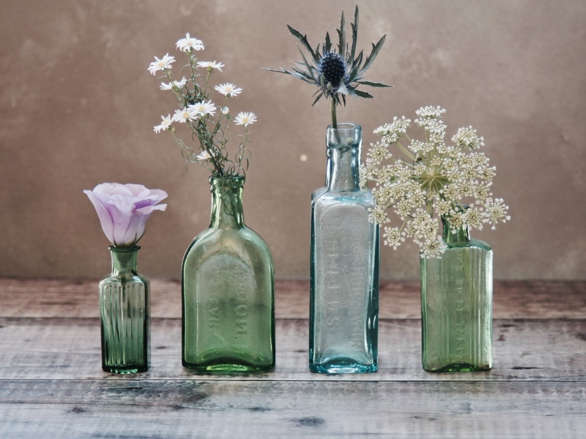 Полевые цветы в стеклянных банках на деревянном столе