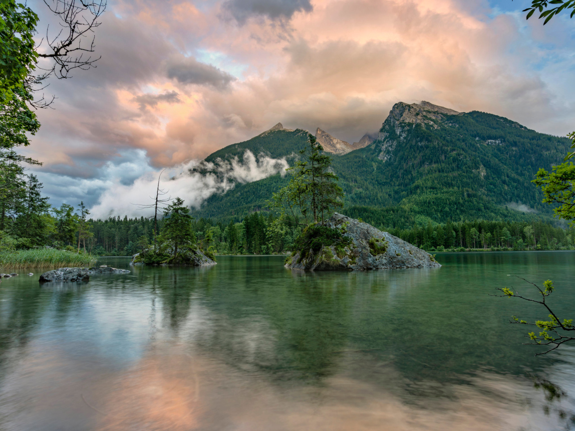 Покрытые зеленью горы в облаках у озера