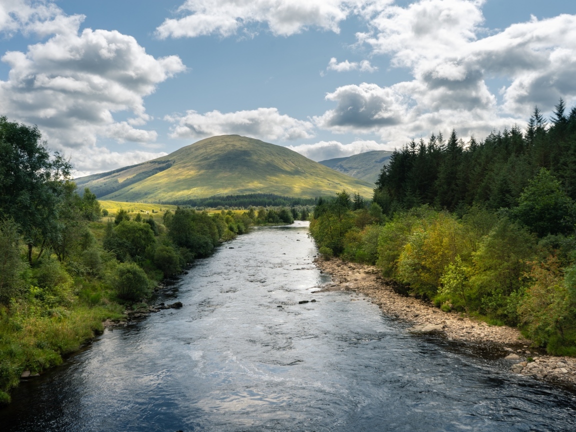 Белые облака в голубом небе над рекой в горах