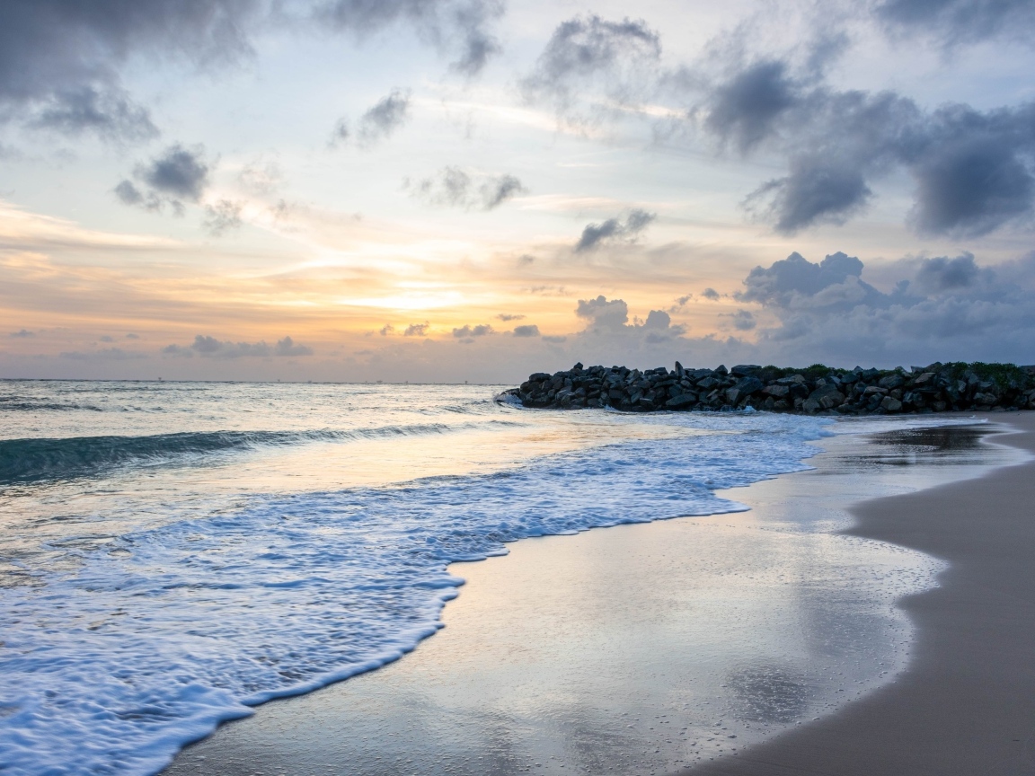 Волны омывают морской песок на рассвете