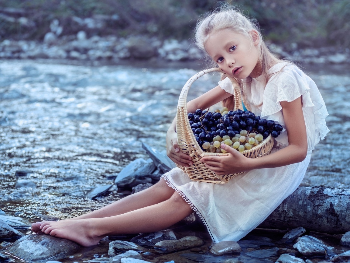 Девочка с корзиной винограда сидит у воды