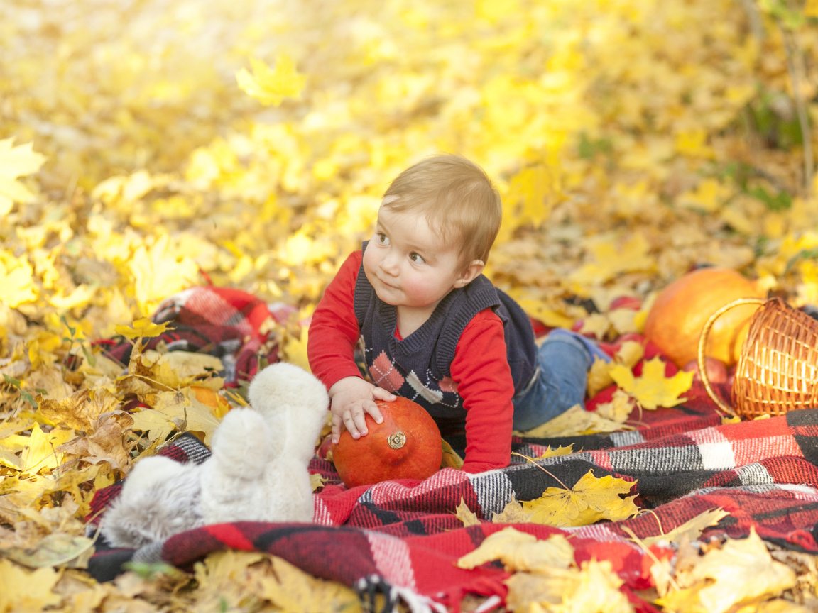 Маленький ребенок лежит на покрывале на земле осенью