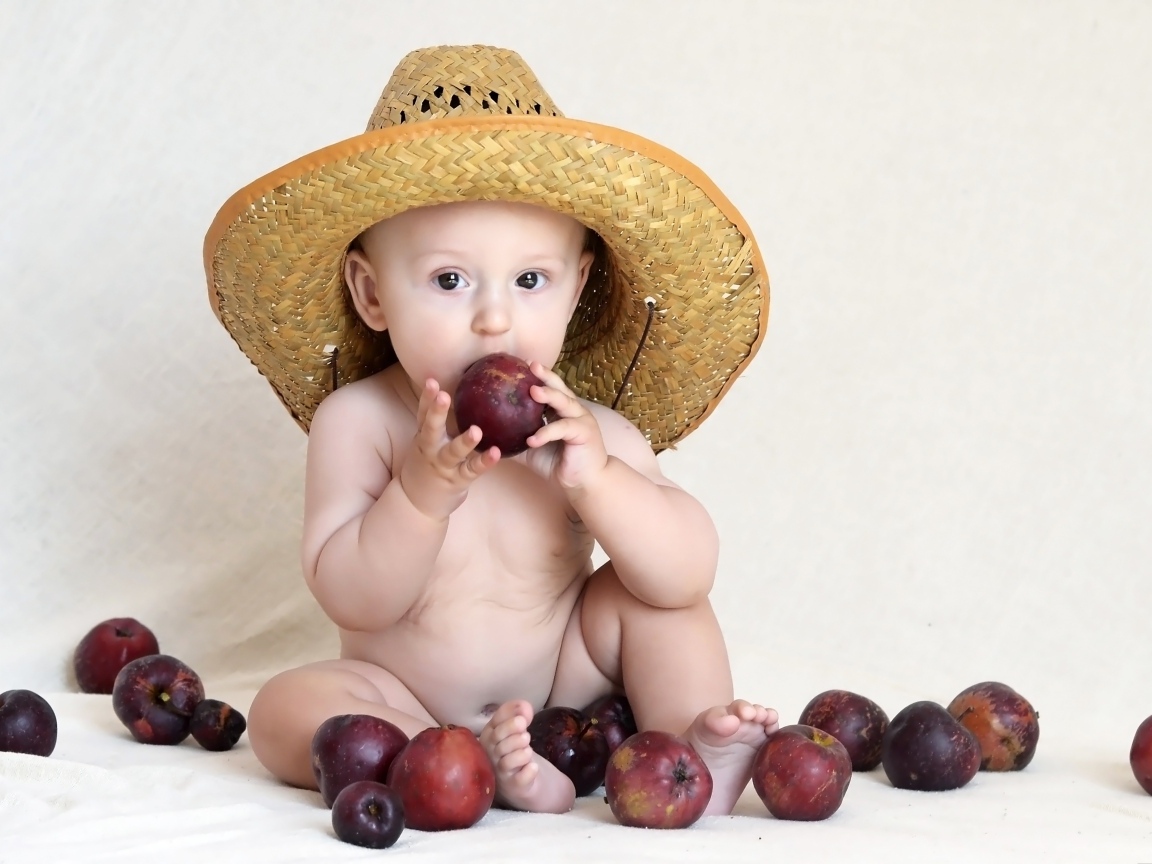 Малыш в шляпе грызет яблоки