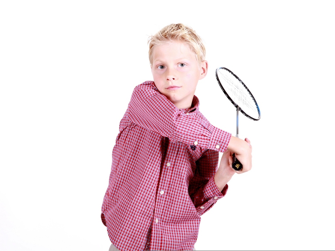 Мальчик в рубашке с ракеткой в руках на белом фоне