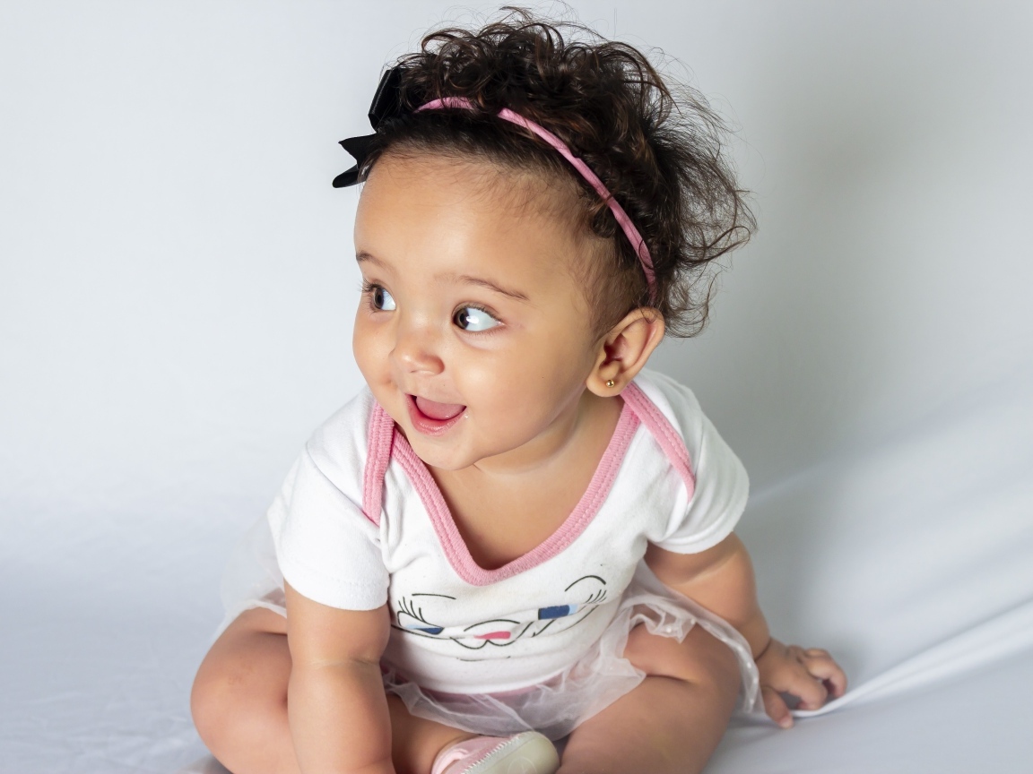 Веселая маленькая девочка с ободком на голове