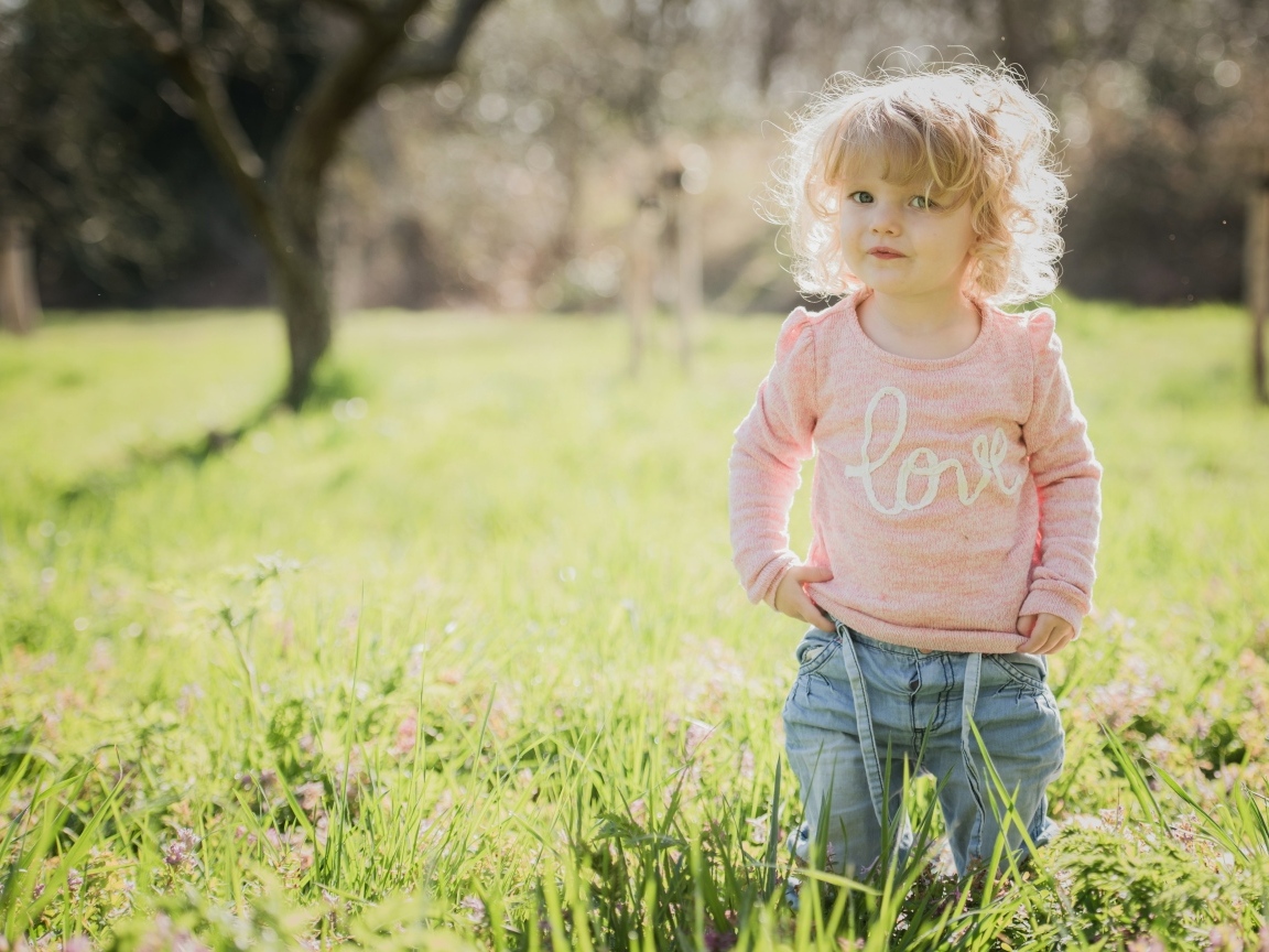 Кудрявая девочка в зеленой траве