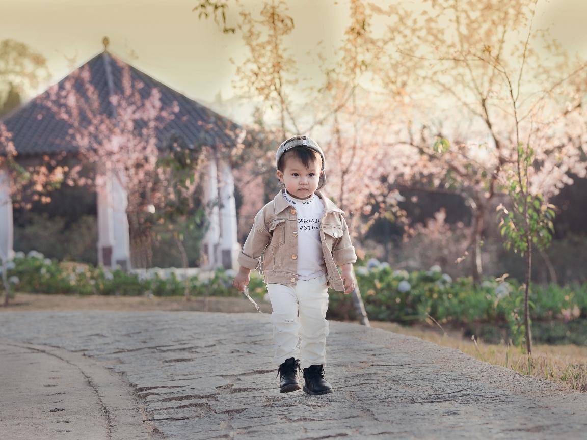 Милый мальчик гуляет по дороге у дома