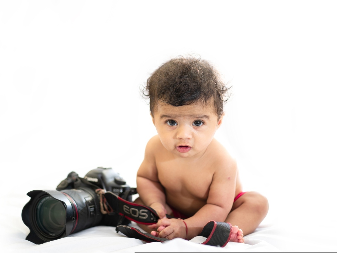 Милый ребенок с фотоаппаратом на белом фоне