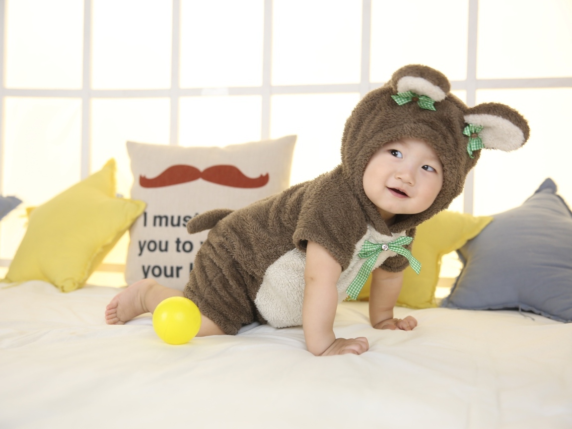 Смешной ребенок азиат в костюме на кровати