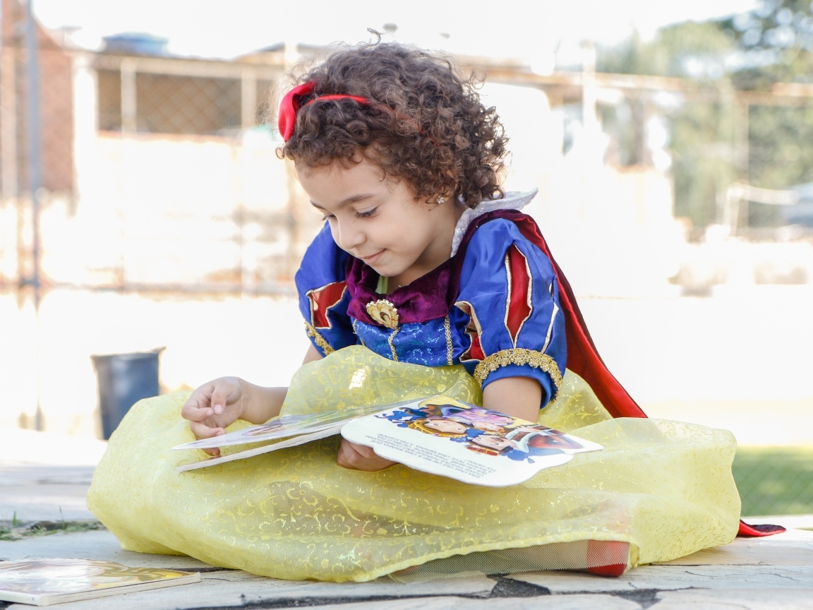 Маленькая девочка в костюме Белоснежки с книгой